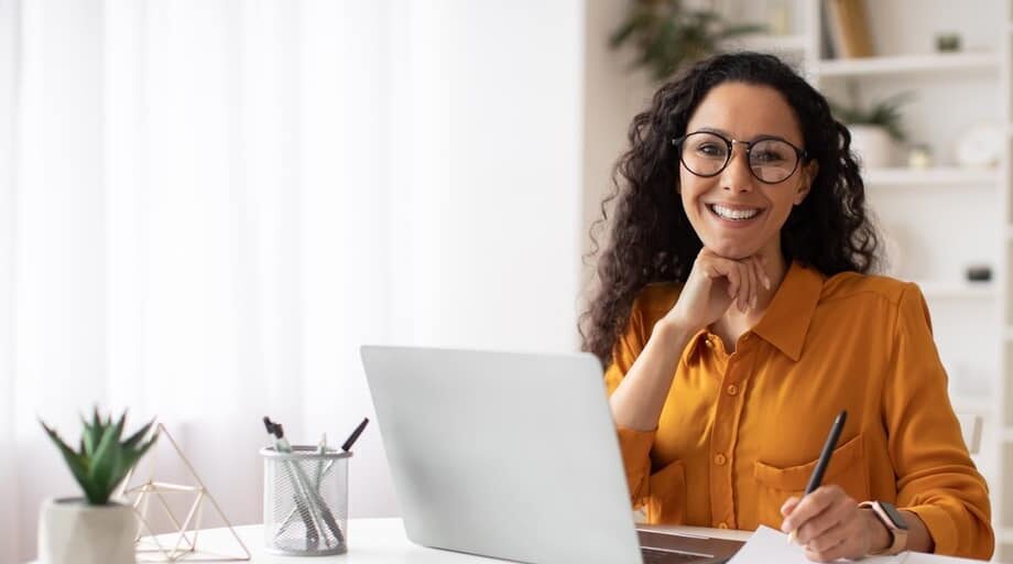 Smiling woman behind her laptop learning about becoming a freelancer through Tentoo